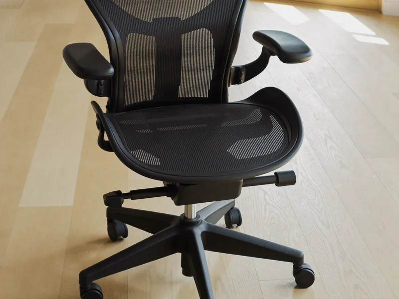 Ergonomischer Netzstuhl mit verstellbaren Armlehnen auf hellem Holzboden
